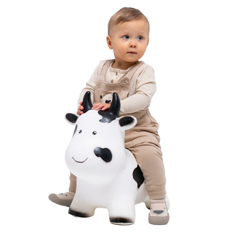 1. Toddler in beige outfit sitting on Gerardo's Toys My First JUMPY white cow hopper toy