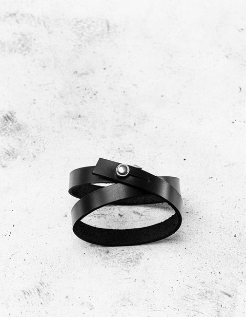 1. Black leather wristband by Stella Soomlais with double wrap design and screw button closure on textured surface