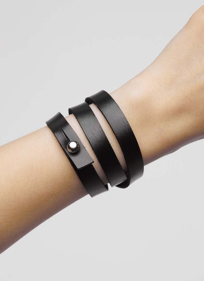 1. Person wearing black leather wristband wrapped twice around wrist with screw button
