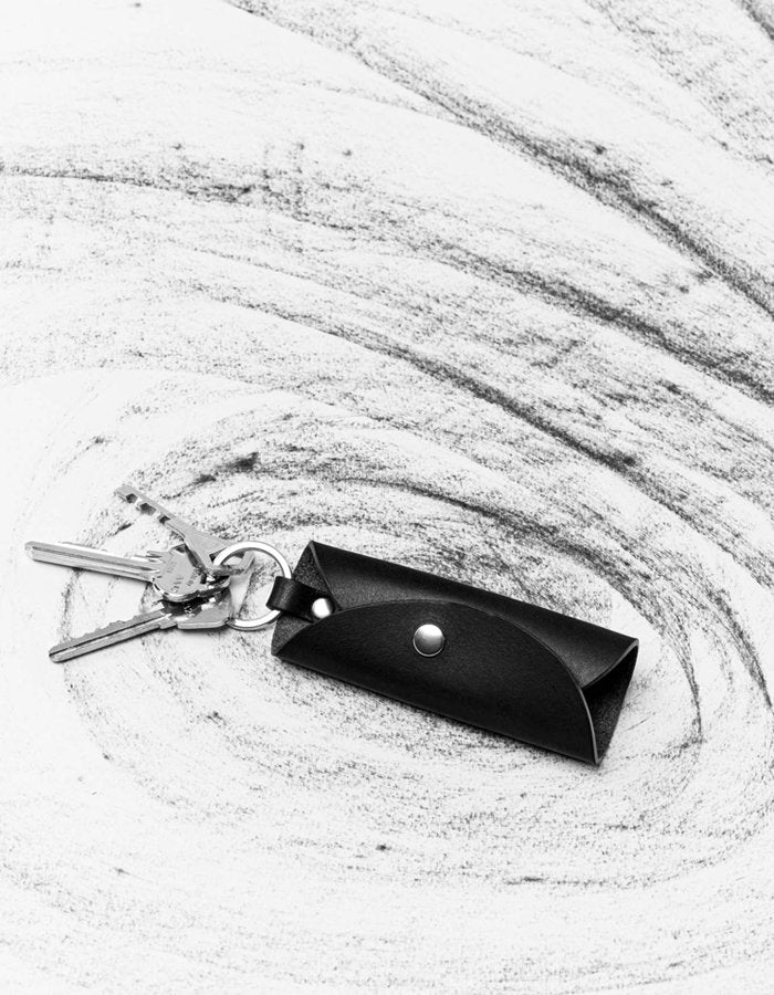 1. Black leather key holder by Stella Soomlais with keys attached, displayed on a textured white background