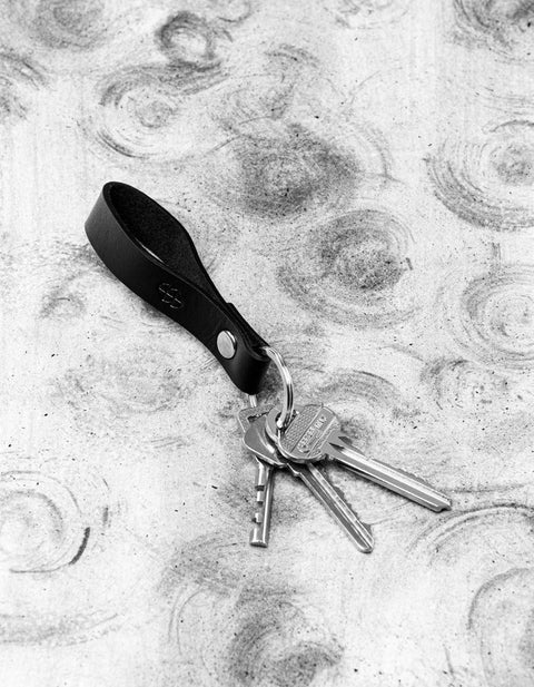 1. Black leather keychain by Stella Soomlais with keys attached, shown on a textured background
