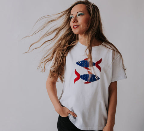 1. Women's Pisces T-shirt in white with fish design, worn by model in lifestyle setting