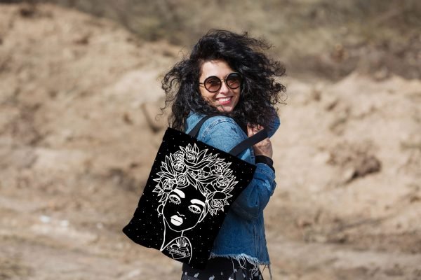 3. Woman smiling with Garbanota Naomi handbag in black, featuring floral haircut design, worn with denim jacket