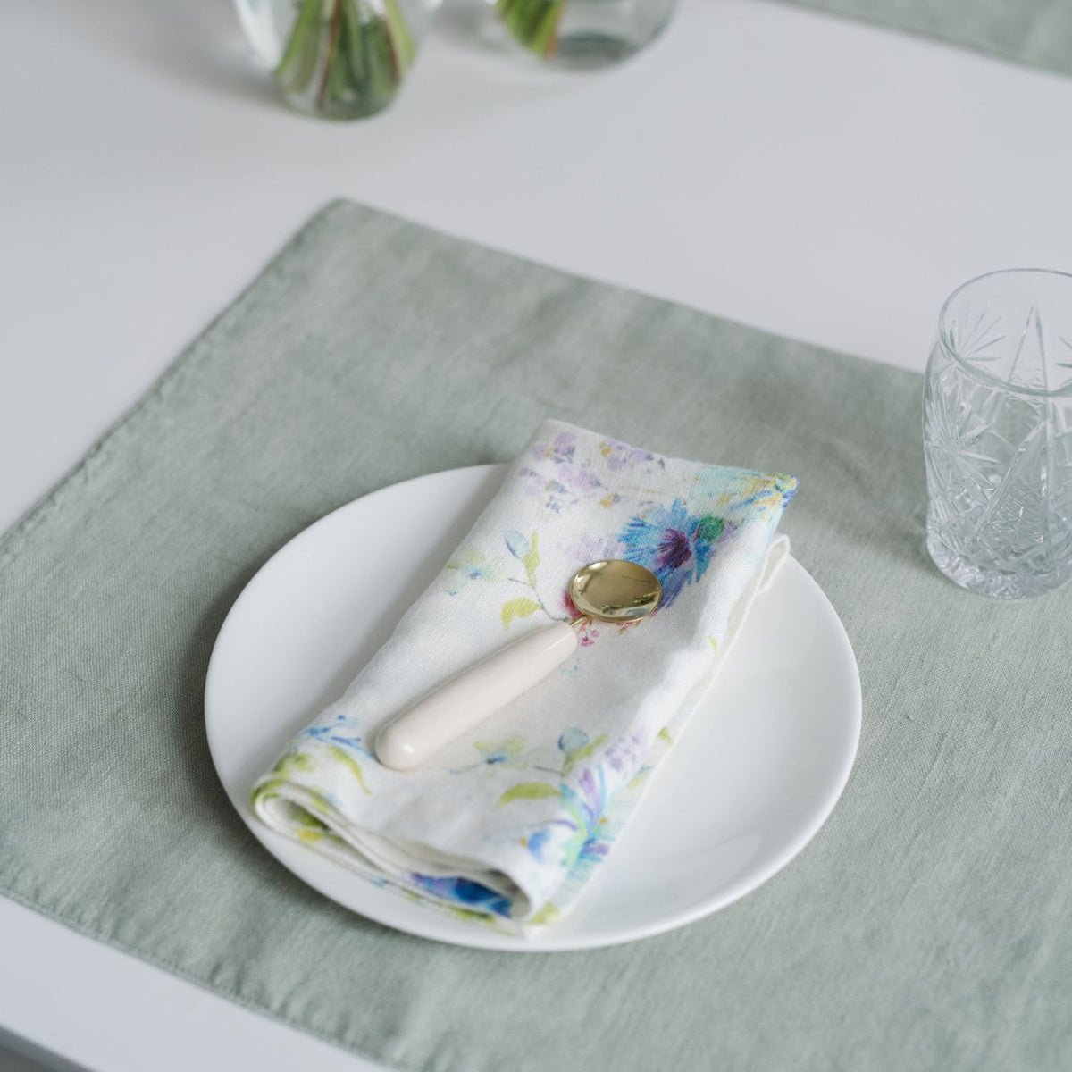 8. Floral linen napkin on a white plate with a decorative spoon on a light green placemat