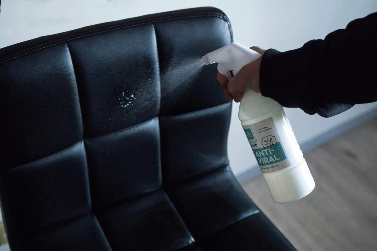 1. GoGoNano Anti-Viral cleaner being sprayed on black leather chair in indoor setting