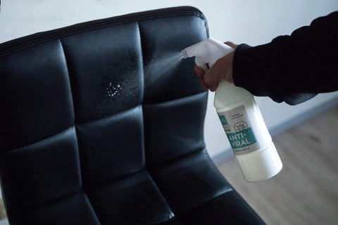 1. GoGoNano Anti-Viral cleaner being sprayed on black leather chair, demonstrating use on furniture