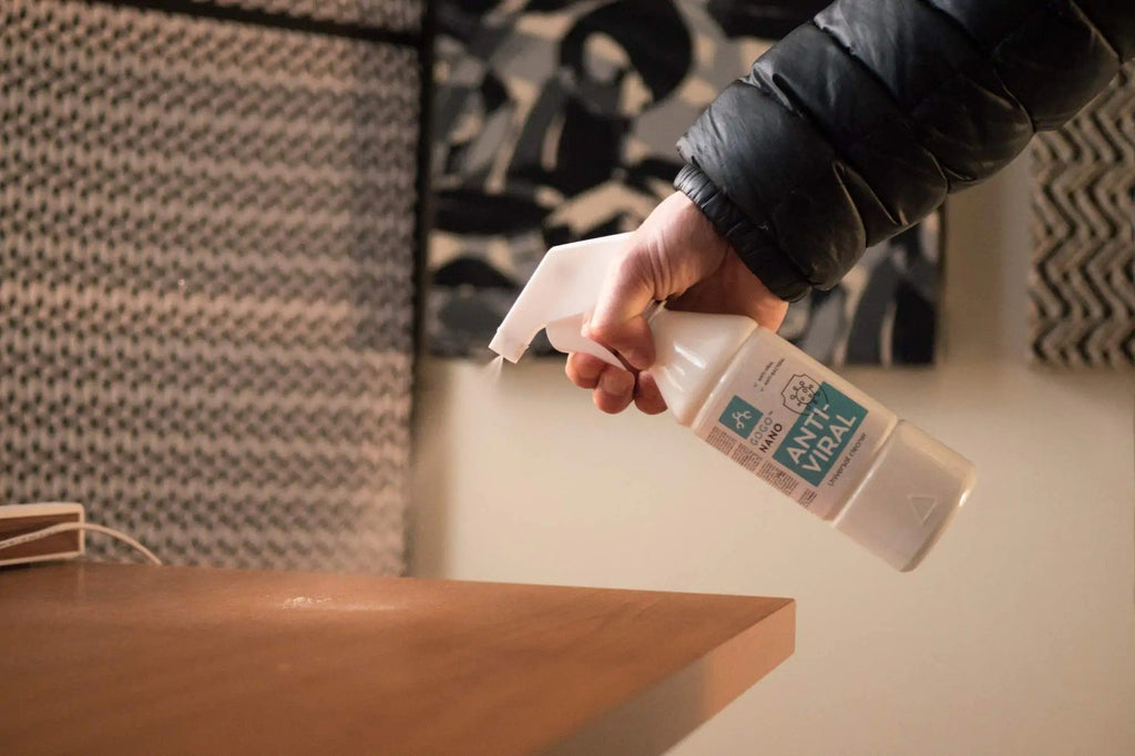 1. Hand spraying GoGoNano Anti-Viral cleaner on wooden table in home environment