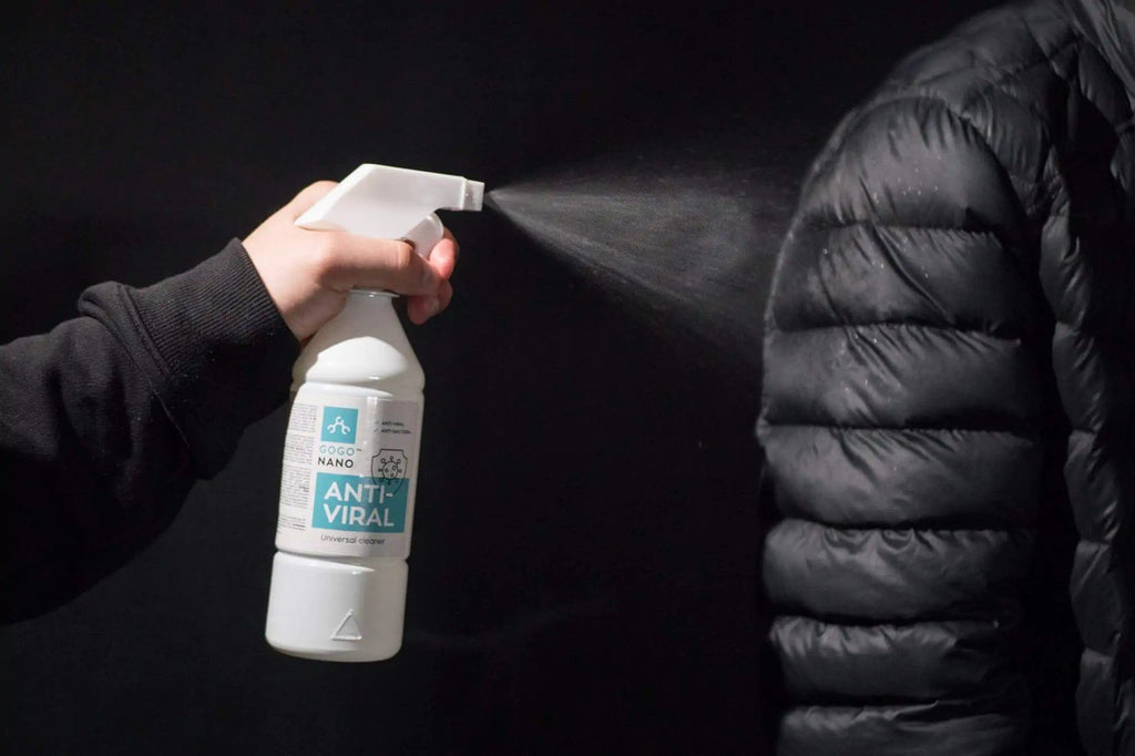 1. Person spraying GoGoNano Anti-Viral cleaner on black jacket in dark setting