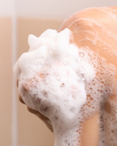 6. Close-up of person lathering soap on shoulder, emphasizing cleansing action