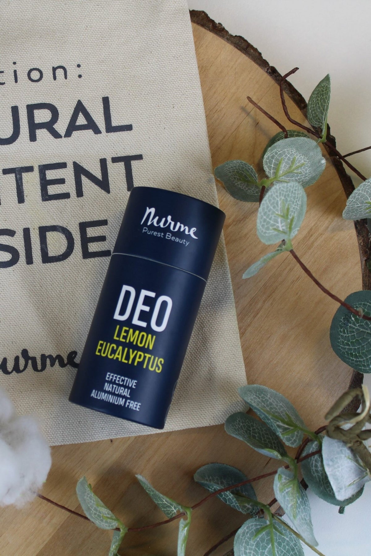 2. Nurme lemon eucalyptus deodorant on wooden surface with cotton and leaves, next to a natural content bag