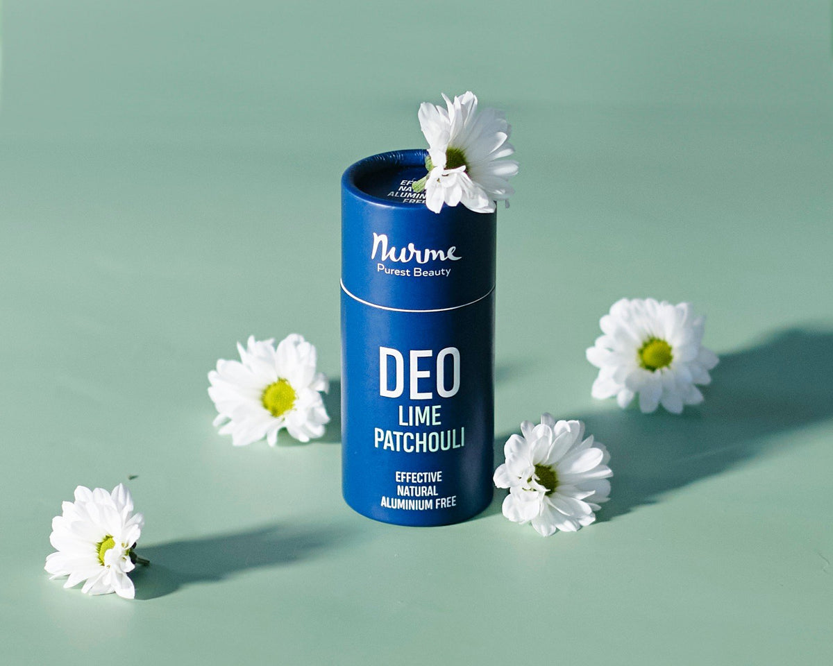 1. Nurme Lime & Patchouli natural deodorant in blue eco-friendly packaging surrounded by white flowers on a green background