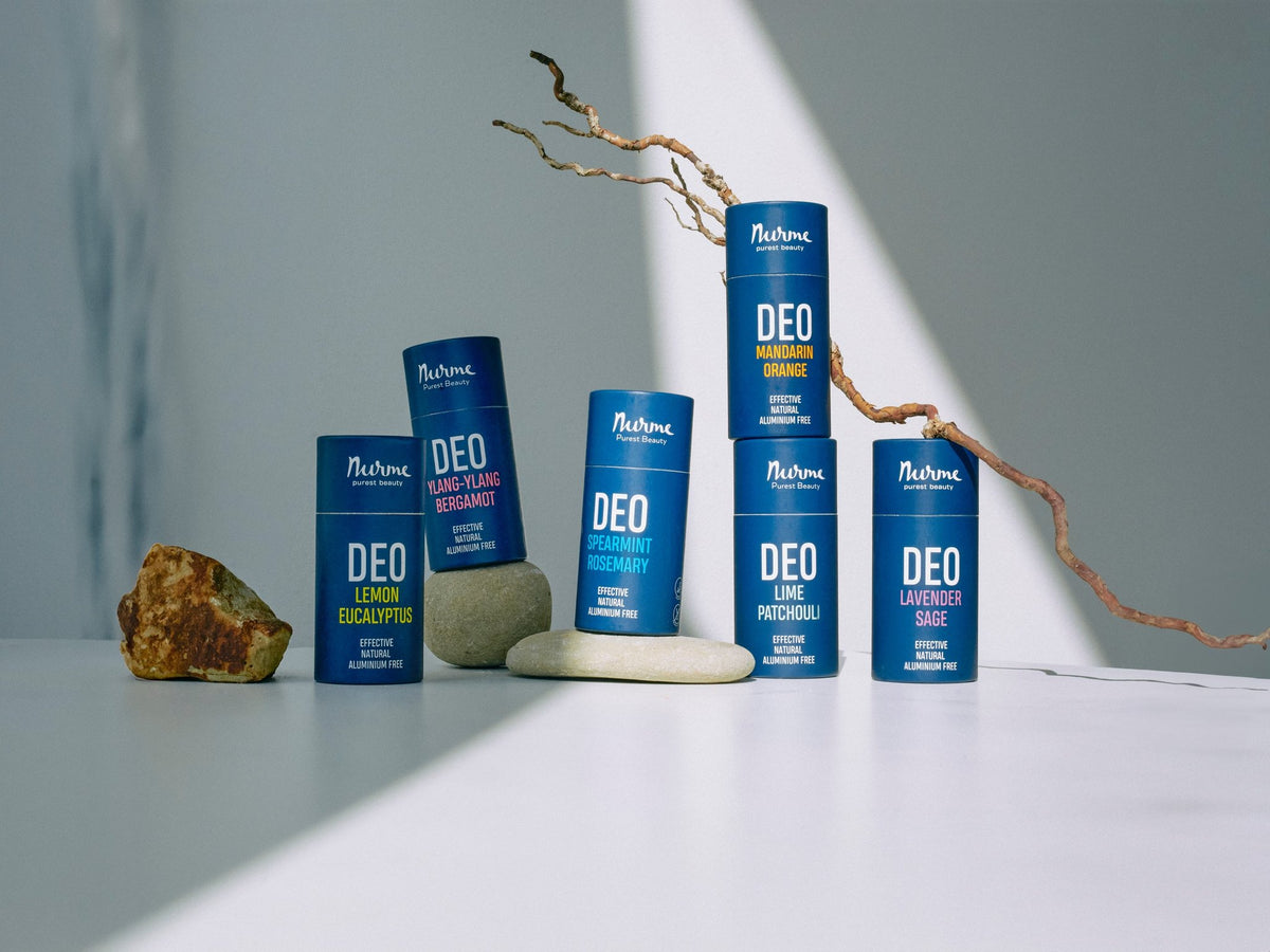 3. Collection of Nurme natural deodorants in various scents on a white surface with natural stones and branches