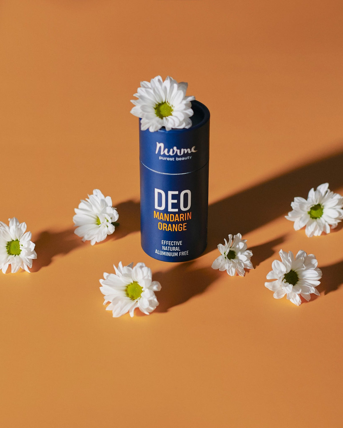 6. Nurme mandarin and orange deodorant on orange background surrounded by white flowers