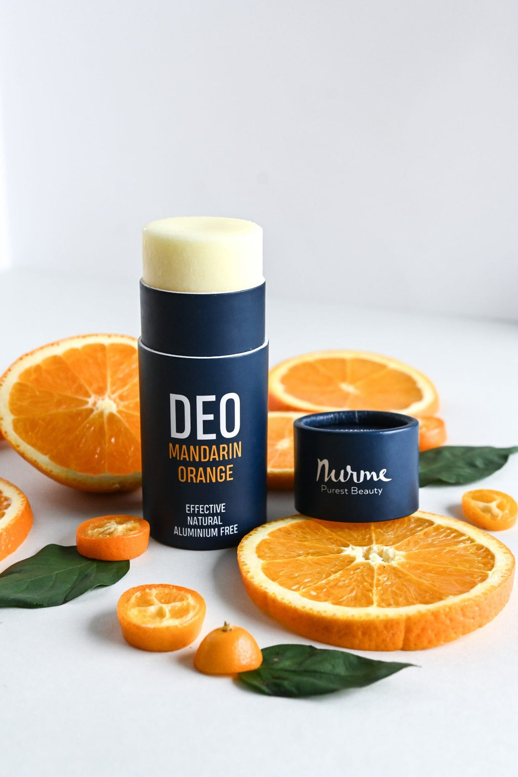 1. Nurme natural deodorant with mandarin and orange on white background surrounded by fresh orange slices and leaves