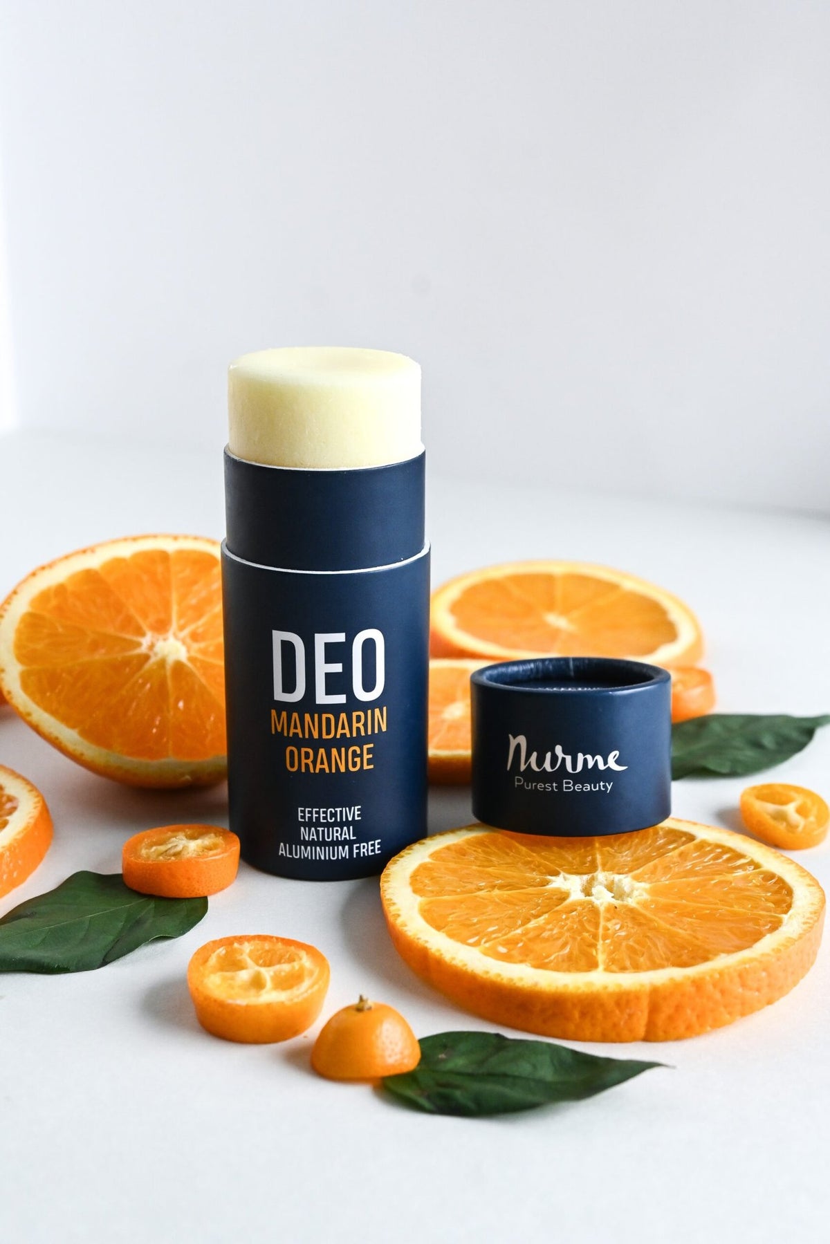 1. Nurme natural deodorant with mandarin and orange on white background surrounded by fresh orange slices and leaves