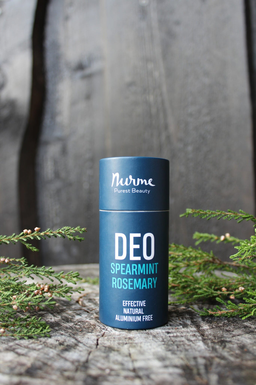 2. Nurme spearmint rosemary natural deodorant on wooden surface with green foliage