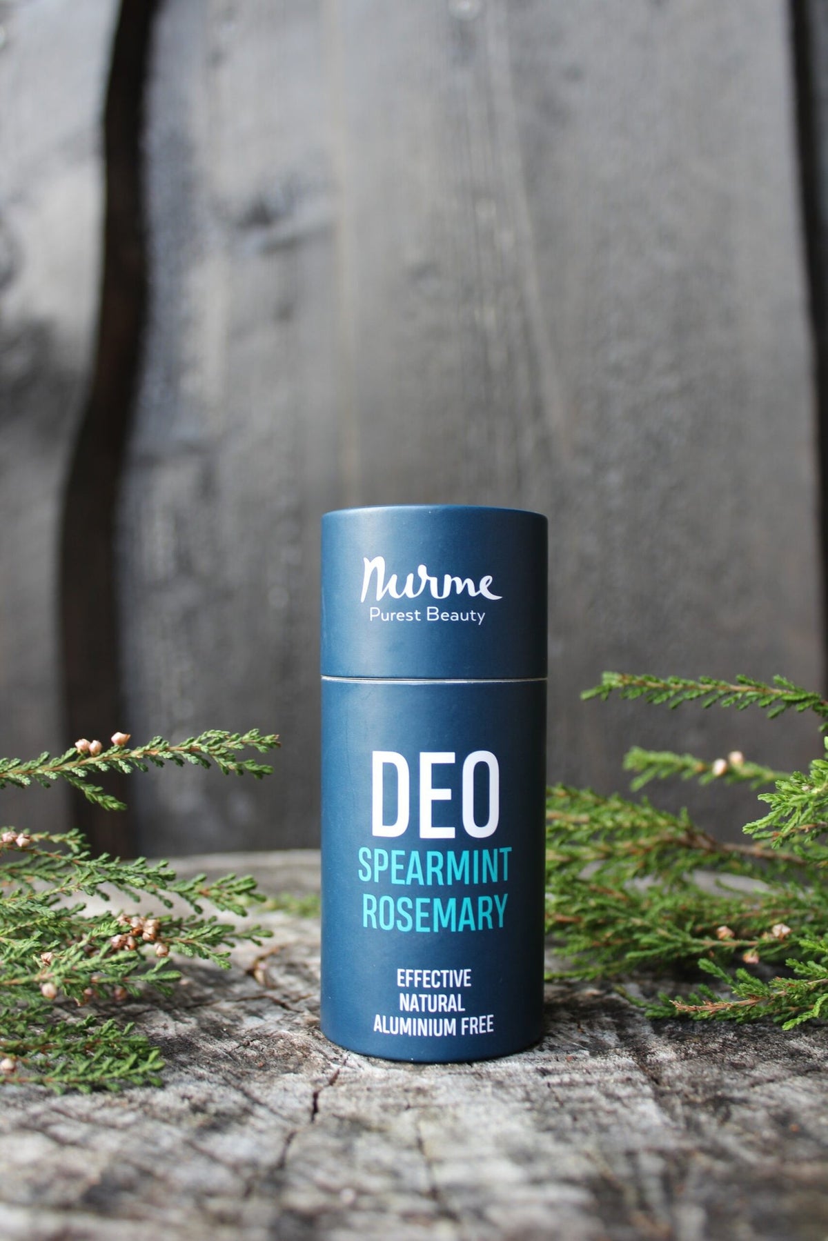 2. Nurme spearmint rosemary natural deodorant on wooden surface with green foliage