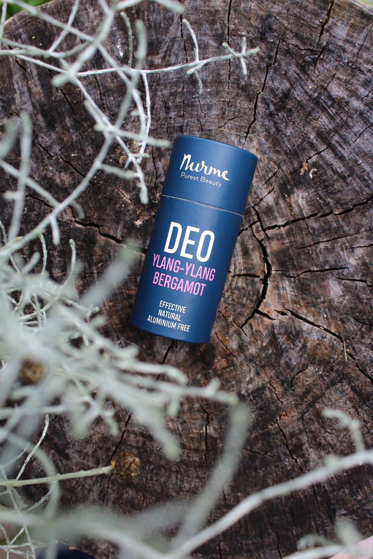 3. Nurme Ylang-Ylang Bergamot deodorant on rustic wooden surface surrounded by natural foliage