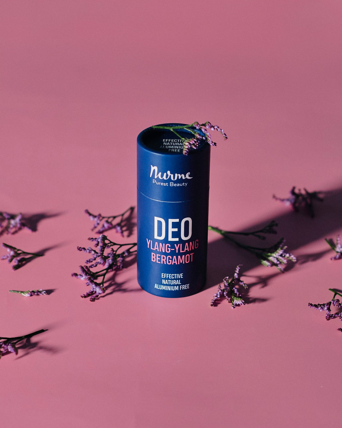 1. Nurme Ylang-Ylang Bergamot deodorant in eco-friendly packaging on pink background with purple flowers