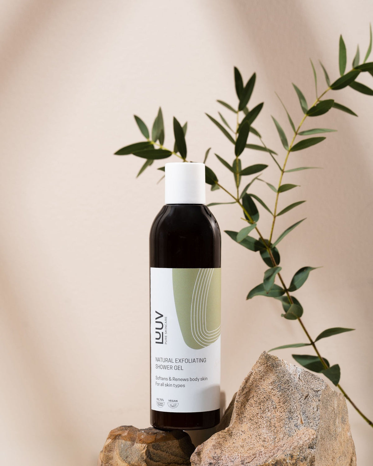1. LUUV Natural Exfoliating Shower Gel bottle placed on rocks with green leaves in background, highlighting eco-friendly theme