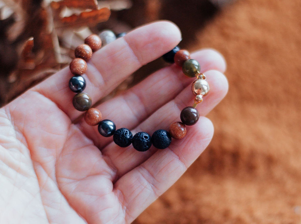 2. Close-up of Natural Lava Bracelet Magic Autumn in hand, showcasing lava rocks, hematite, Indian agate, and goldstone beads with golden magnetic closure