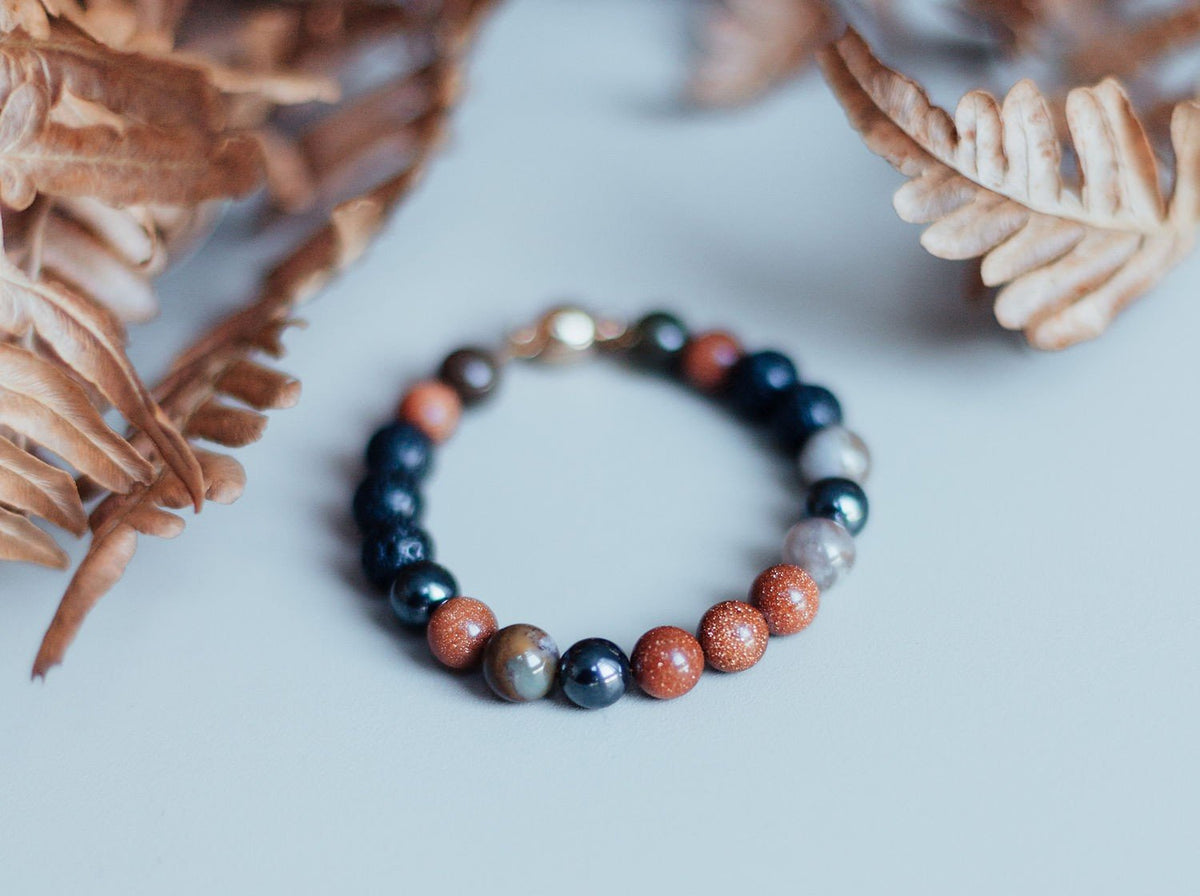 4. Studio shot of Natural Lava Bracelet Magic Autumn by Canary Lava, featuring lava rocks, hematite, Indian agate, and goldstone beads with autumn leaves