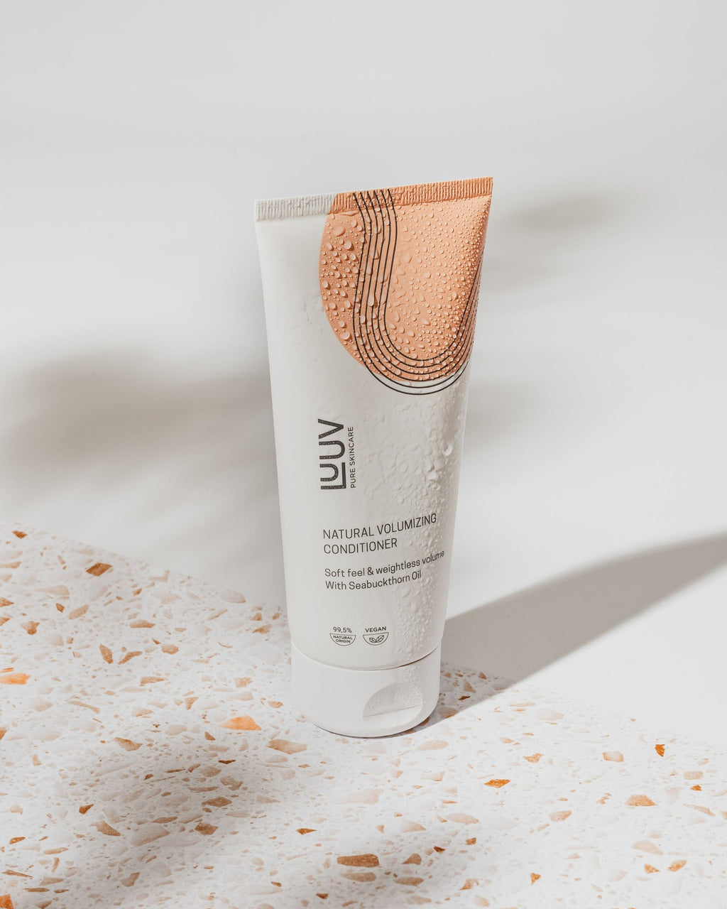 3. LUUV Natural Volumizing Conditioner with sea buckthorn oil, featuring water droplets on a terrazzo surface