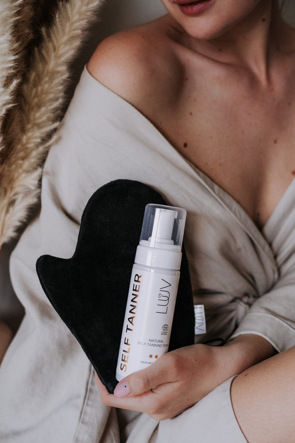1. Woman holding LUUV Tanning Mitt and self-tanner bottle, showcasing luxurious application for a flawless tan