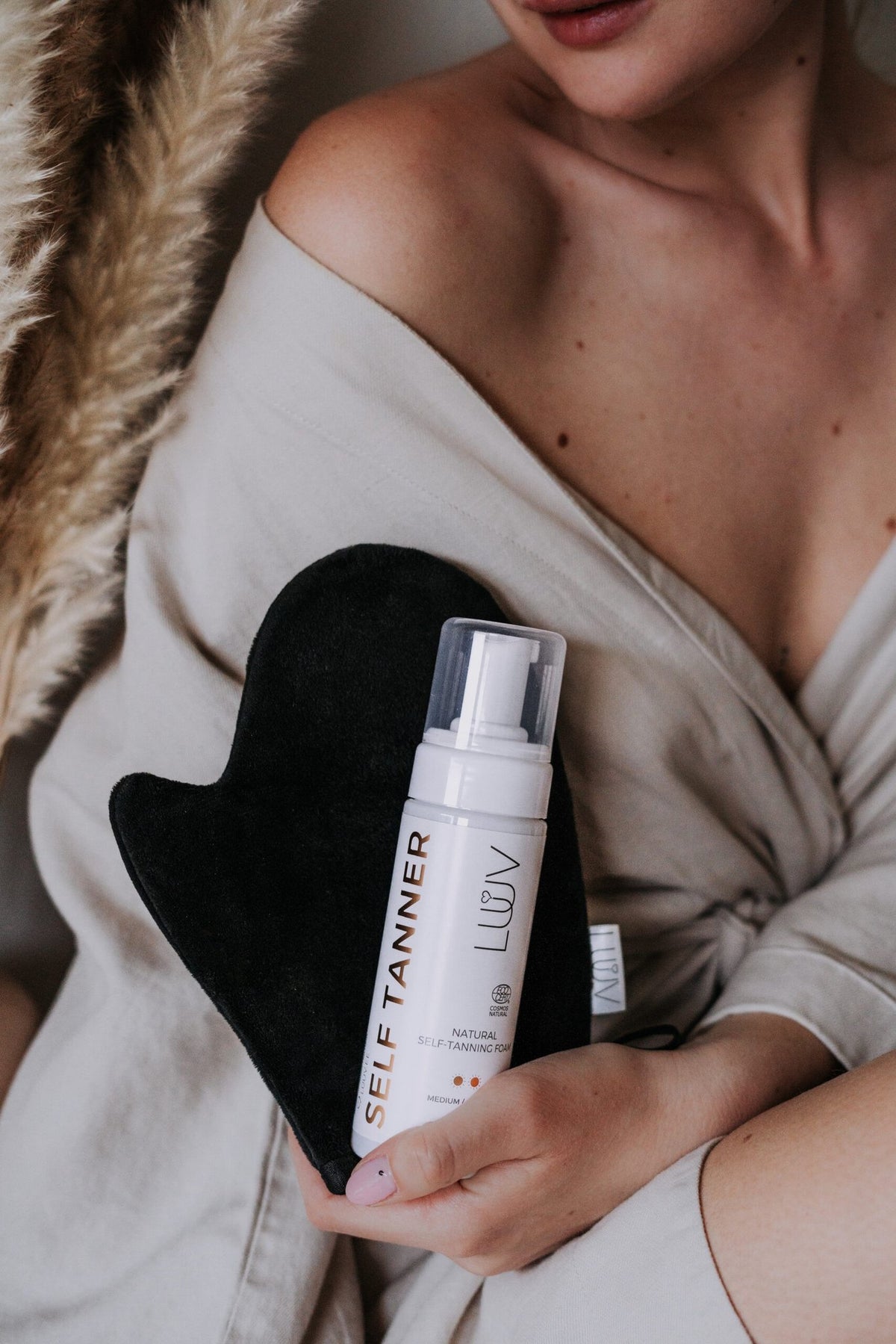 1. Woman holding LUUV Tanning Mitt and self-tanner bottle, showcasing luxurious application for a flawless tan