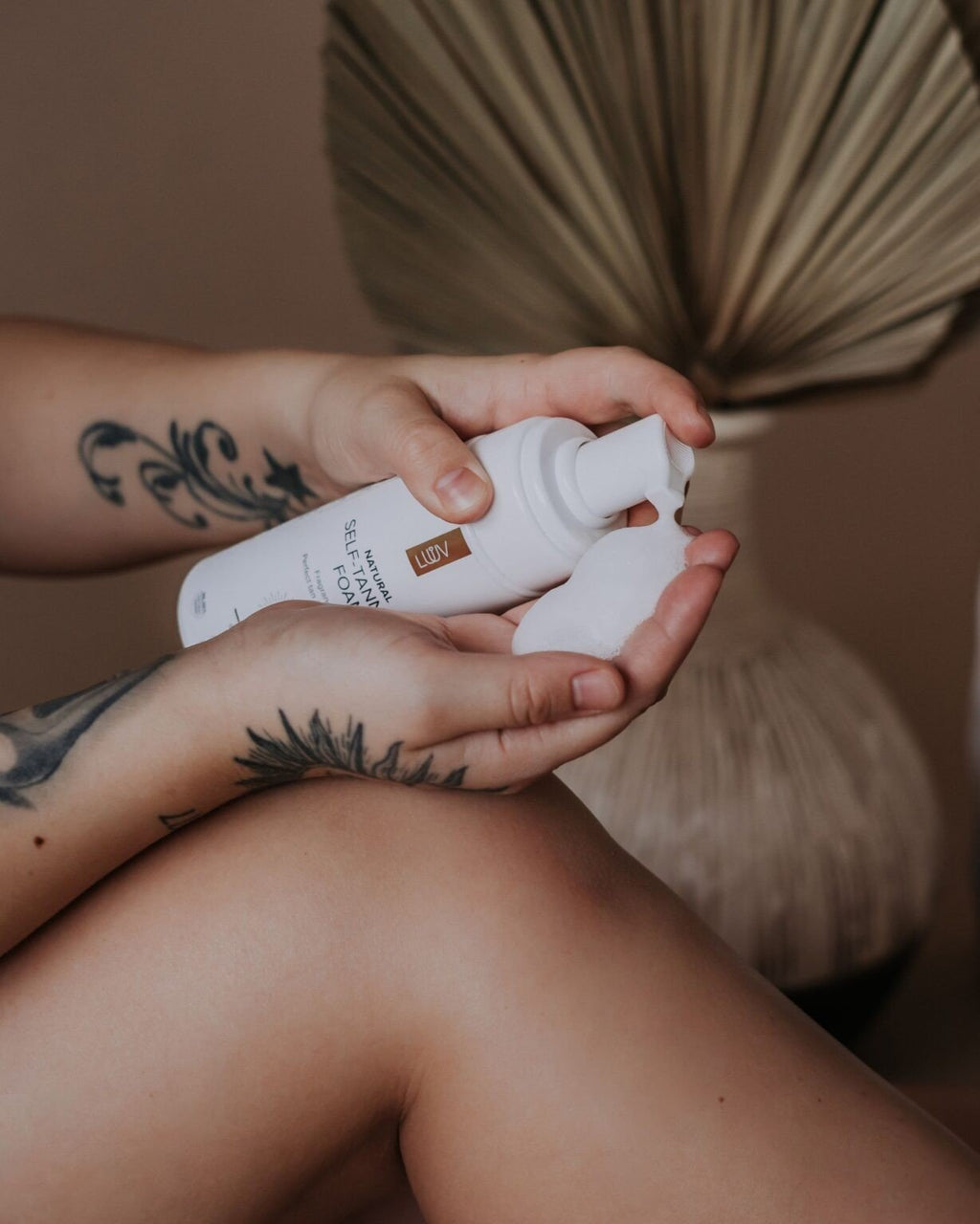2. Close-up of LUUV Natural Self Tanning Foam being dispensed onto hand, highlighting texture