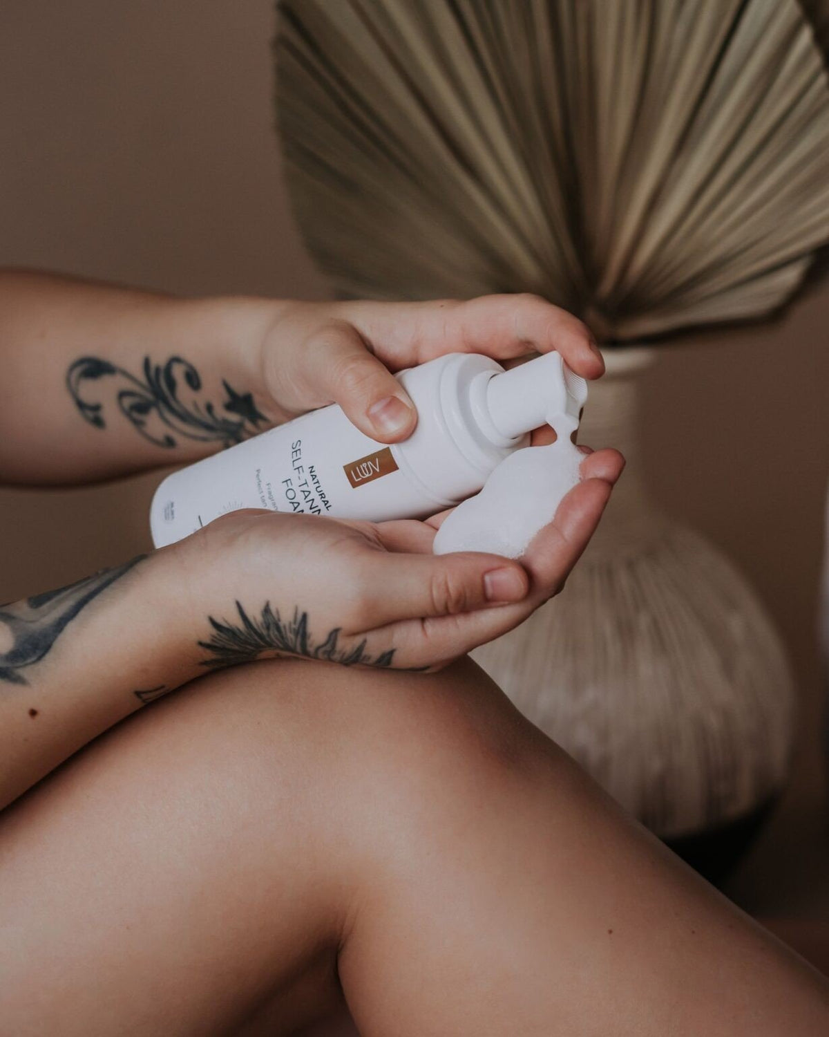 2. Close-up of LUUV Natural Self Tanning Foam being dispensed onto hand, highlighting texture