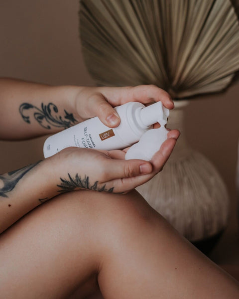 2. Close-up of LUUV Natural Self Tanning Foam being dispensed onto hand, highlighting texture