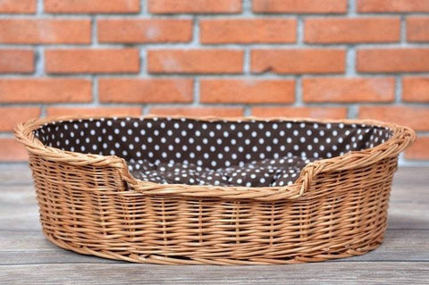1. Natural wicker dog bed with polka dot cushion on wooden floor against brick wall