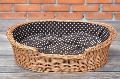 1. Natural wicker dog bed with polka dot cushion on wooden floor against brick wall