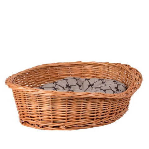 3. Angled view of oval wicker dog bed with soft beige cushion, showcasing handwoven design