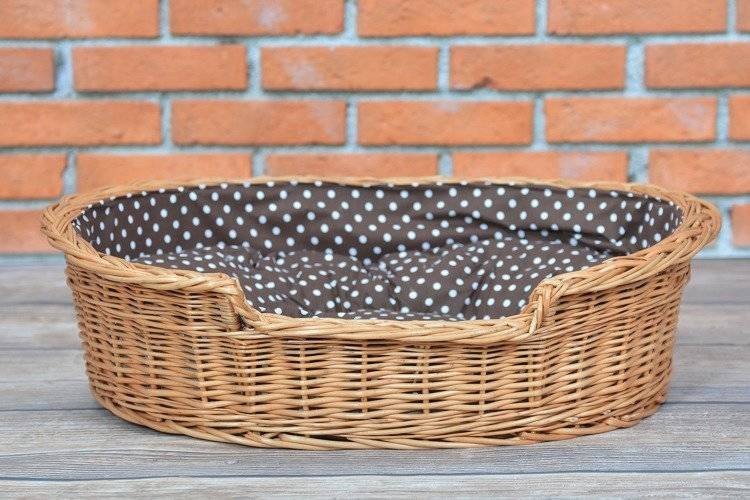 1. Natural wicker dog bed with polka dot cushion on wooden floor against brick wall