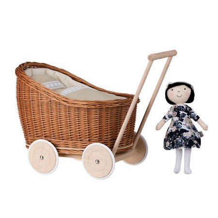 5. Natural wicker doll pram with beige bedding and a doll standing beside it