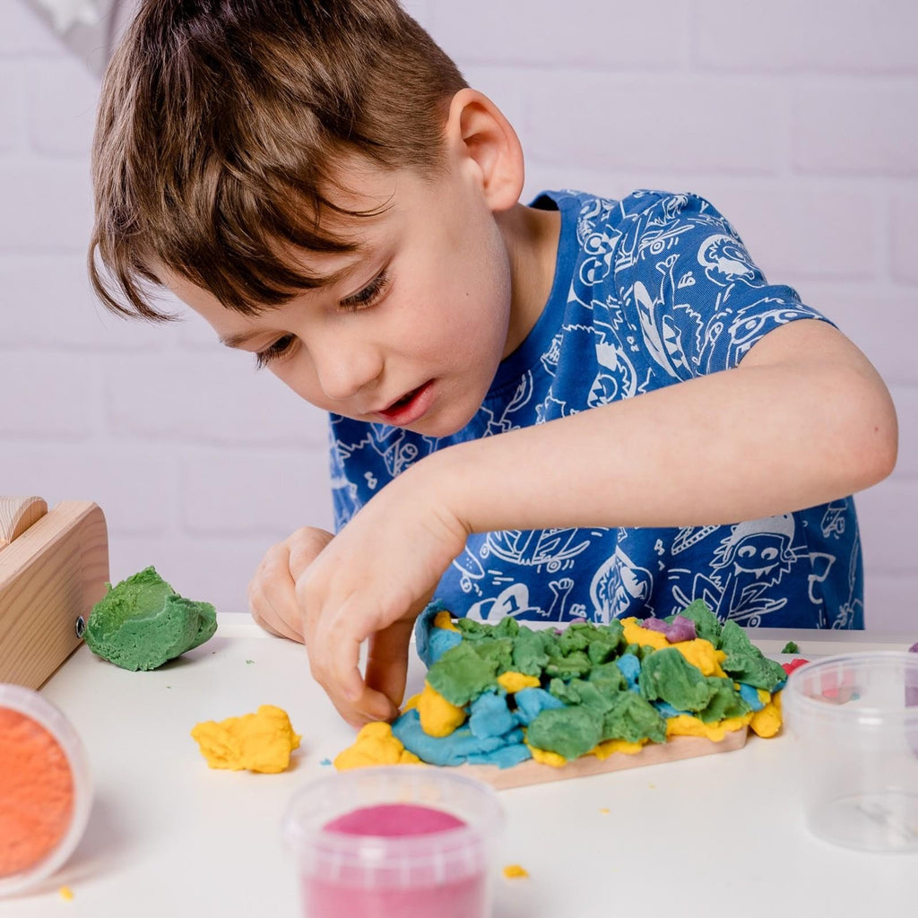 5. Boy focused on shaping Neogrün Easy Clay in green and yellow on a white table