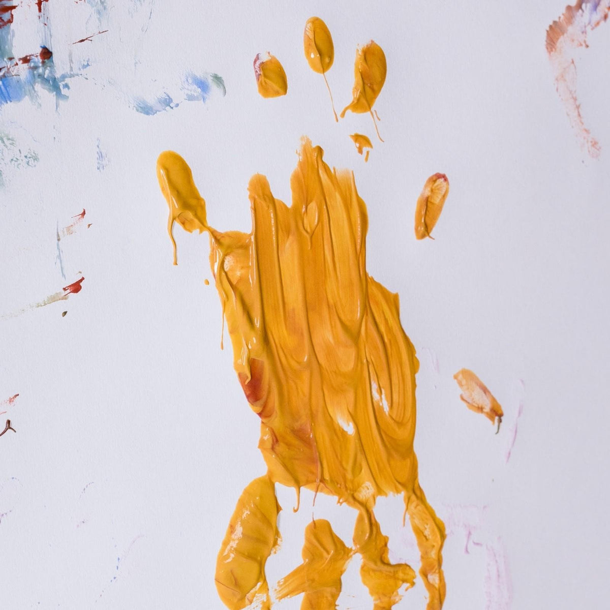 3. Close-up of yellow finger paint handprint on white paper with colorful smudges