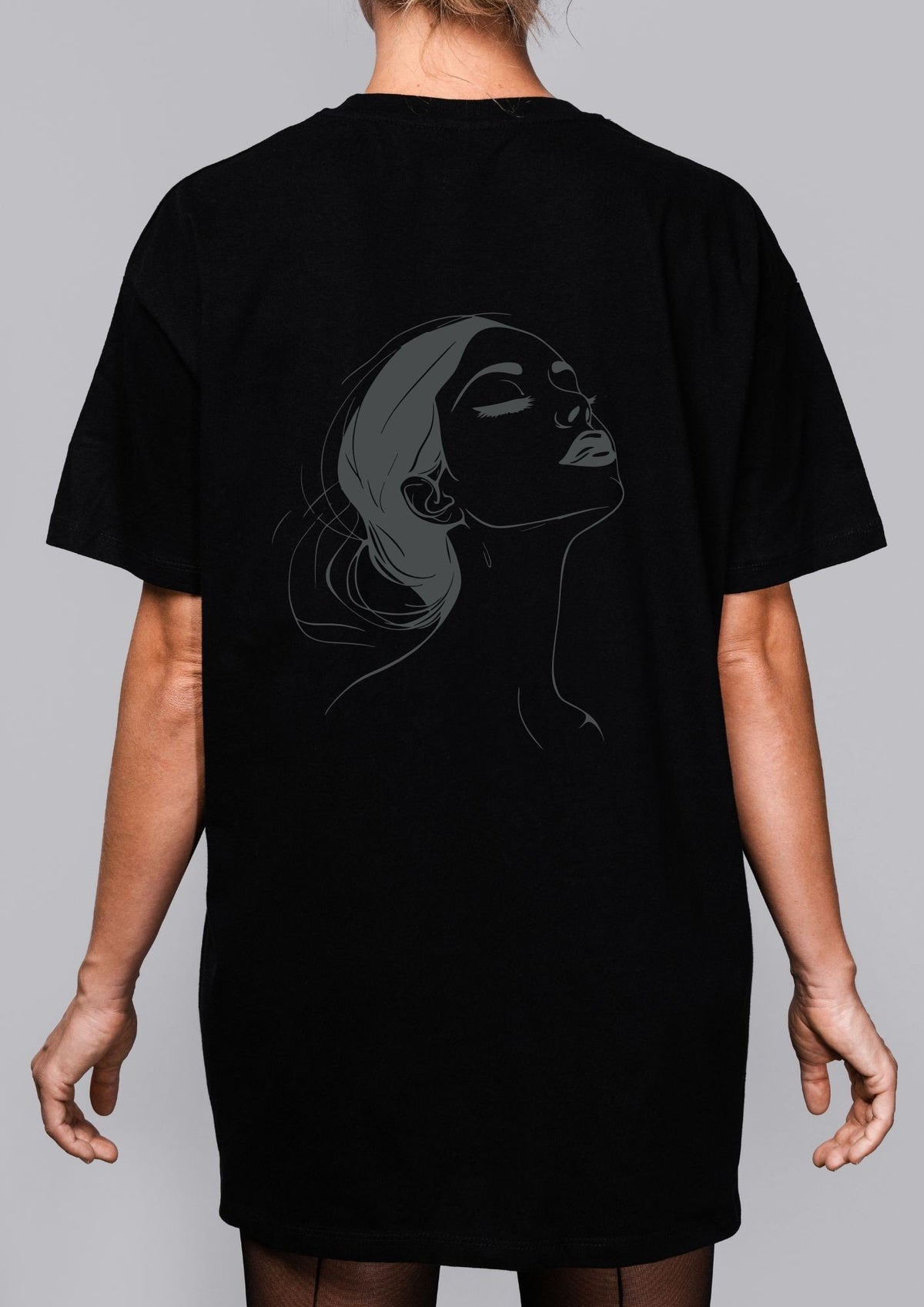3. Woman shown from back wearing black T-shirt with subtle black line art illustration on grey background