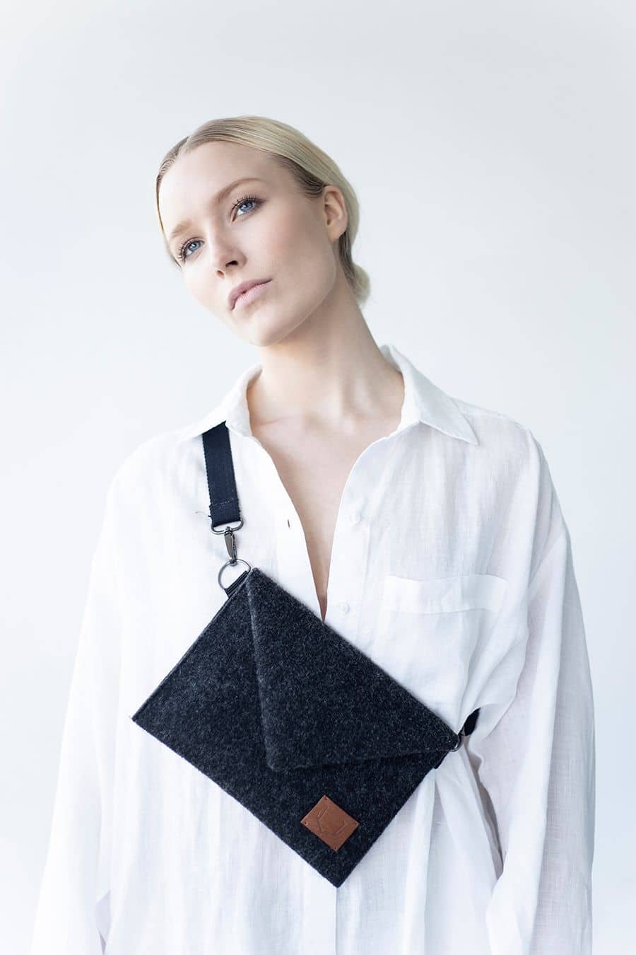 3. Women's Skive-mini crossbody bag by Nordhale worn over shoulder, shown with white shirt in studio