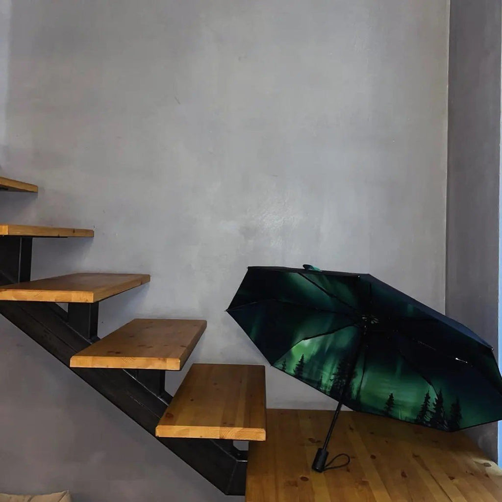 3. Norrsken umbrella with Northern Lights design open on wooden staircase indoors