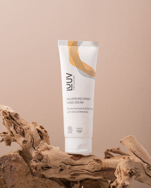 1. LUUV Nourishing Honey Hand Cream tube on natural wood background, highlighting eco-friendly packaging and beeswax ingredient