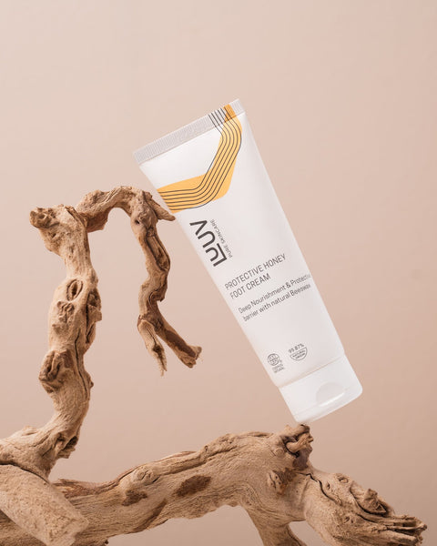 1. LUUV Protective Honey Foot Cream tube on textured wood against beige background