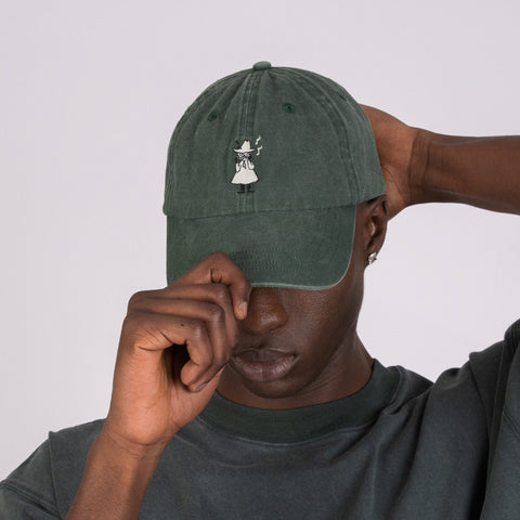 1. Men's green washed denim cap by Moomin, worn by model adjusting brim in studio setting