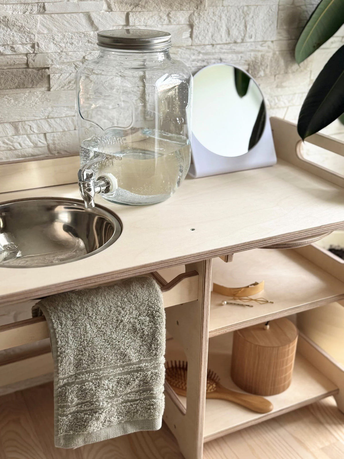 15. Montessori washbasin with enamel bowl, towel, and mirror in a natural setting