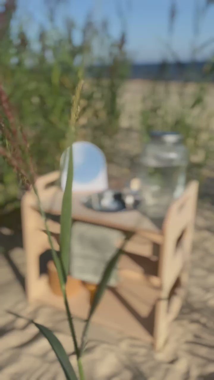 6. Montessori washbasin set outdoors on sandy ground with plants, featuring a mirror and glass jar