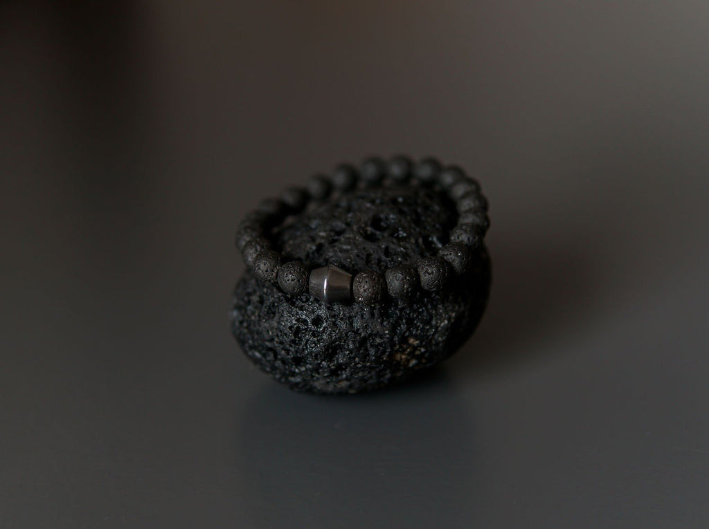 3. Close-up of Obsidian Lava Stone Bracelet by Canary Lava on lava rock, highlighting texture and Obsidian stone