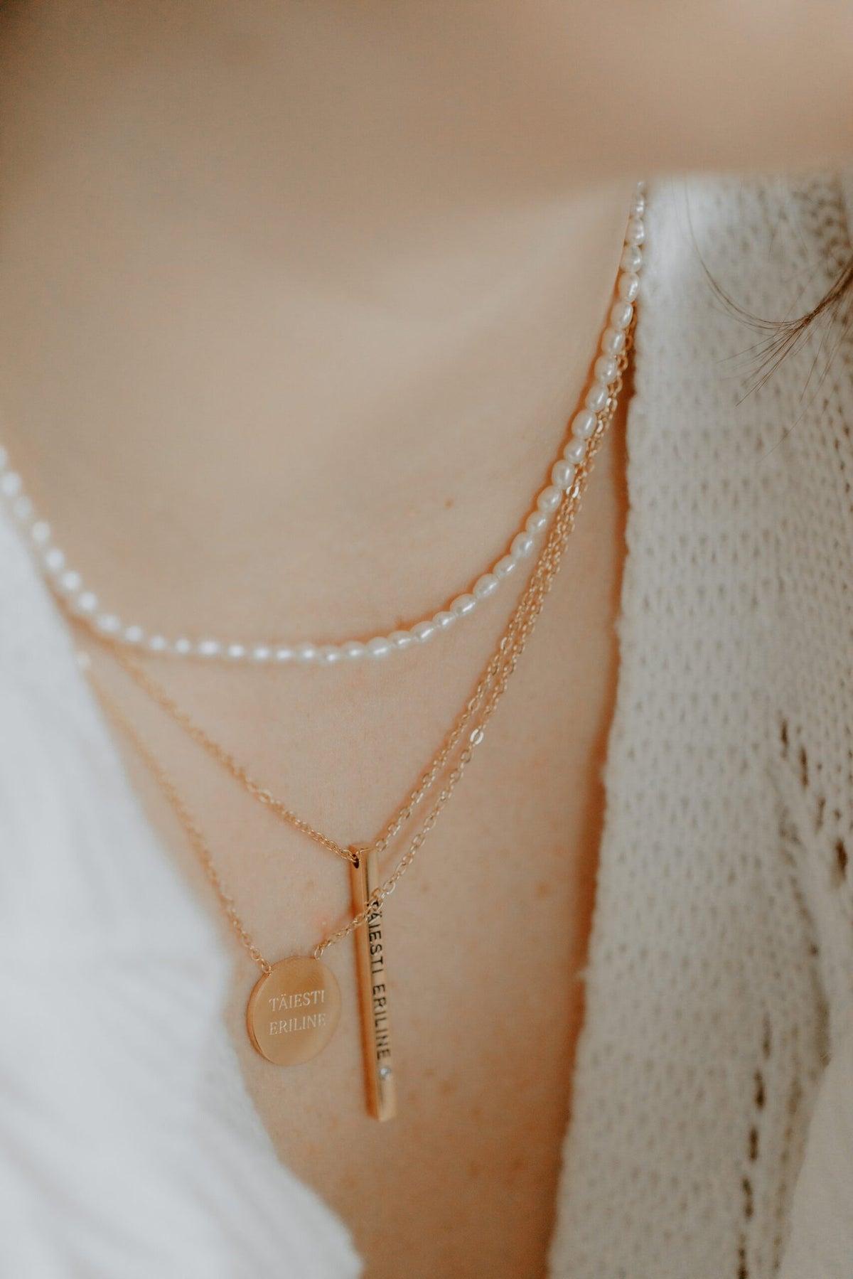 1. Women's layered necklace set featuring Olla's freshwater pearl necklace in gold, styled with additional gold chains, worn with a white knit top