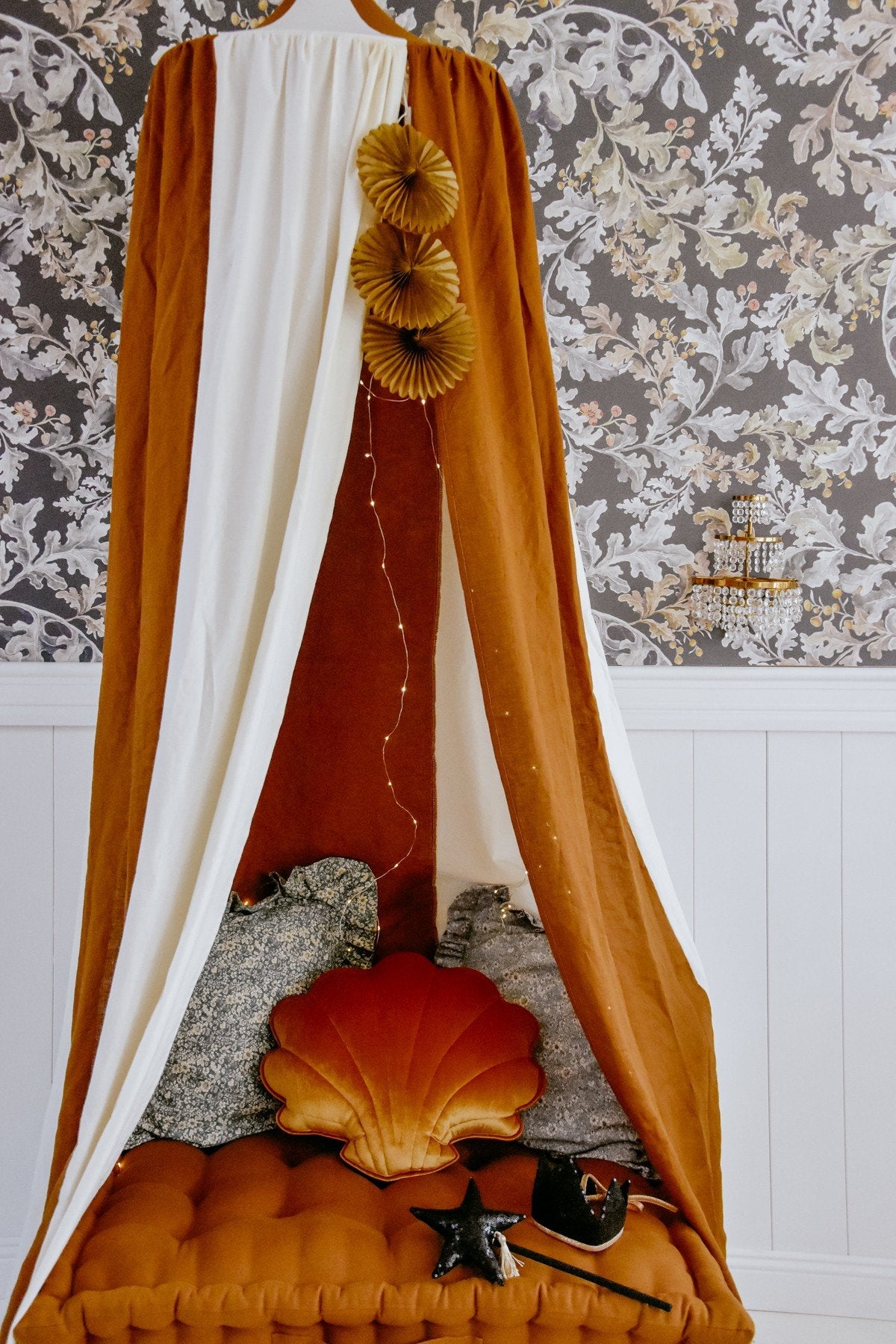 13. Caramel and cream canopy over a bed with decorative pillows and floral wallpaper
